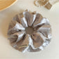 Close-up of Gifty satin scrunchie showing smooth fabric and polka dot design