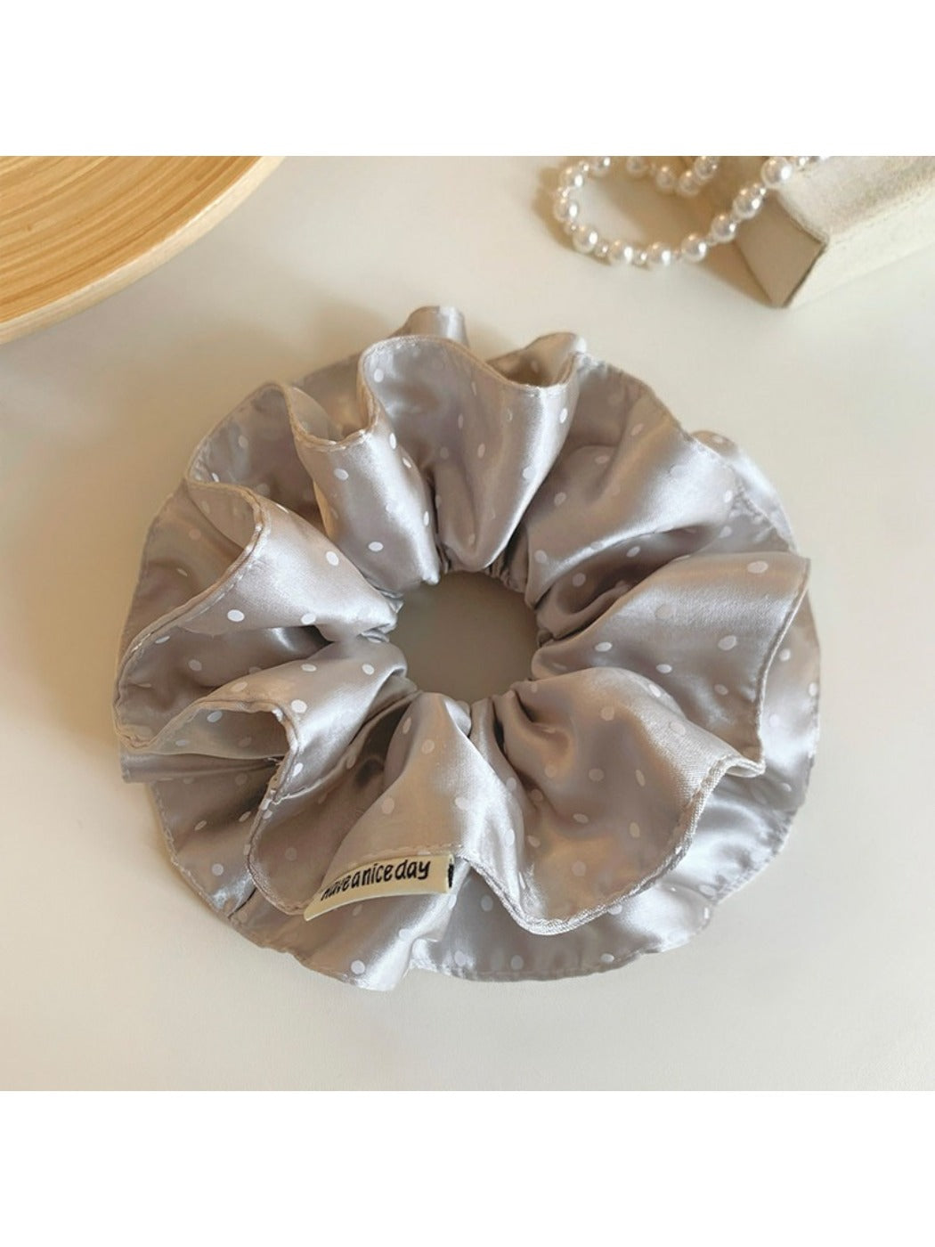 Close-up of Gifty satin scrunchie showing smooth fabric and polka dot design