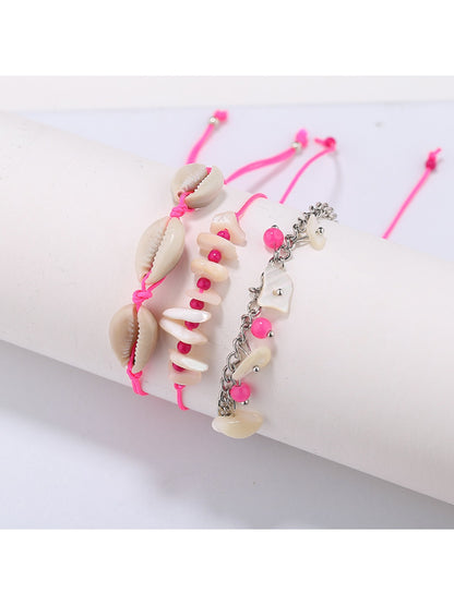 Lovra beach style bracelet coiled on a sandy surface with ocean waves in background