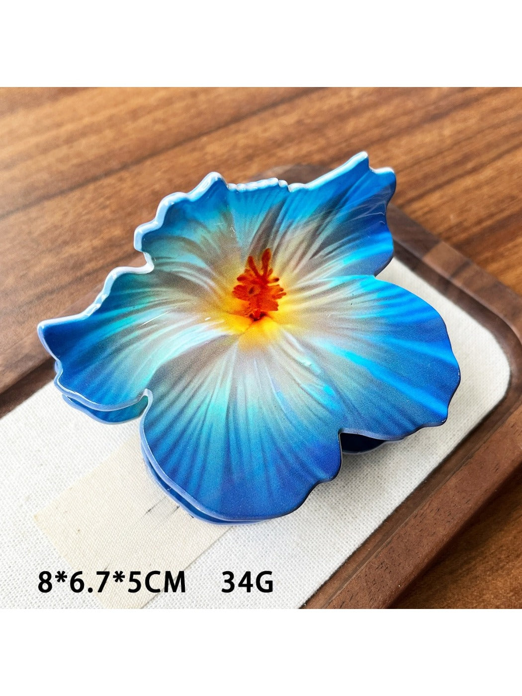 Beau hibiscus claw clip in soft pink resting on a wooden surface