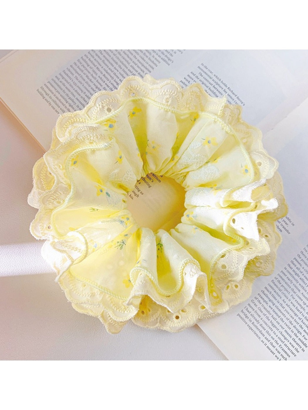 Yellow ruffle scrunchie styled on a model's wrist against a white background