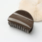 Beau hair clip held between fingers showing size and matte gold texture