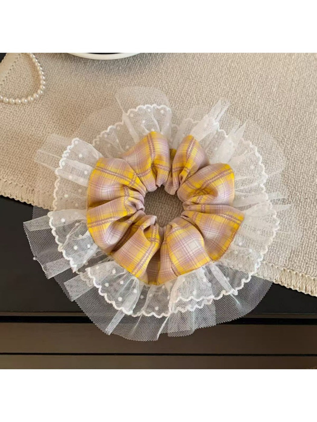 Vintage yellow plaid scrunchie held in hand against neutral background