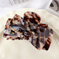 Beau claw clip resting on fabric surface emphasizing glossy texture