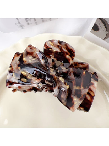 Beau claw clip resting on fabric surface emphasizing glossy texture