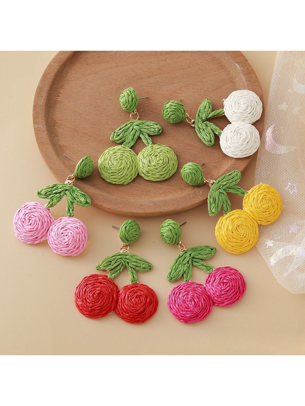 Close-up of raffia woven cherry shaped earrings on white background