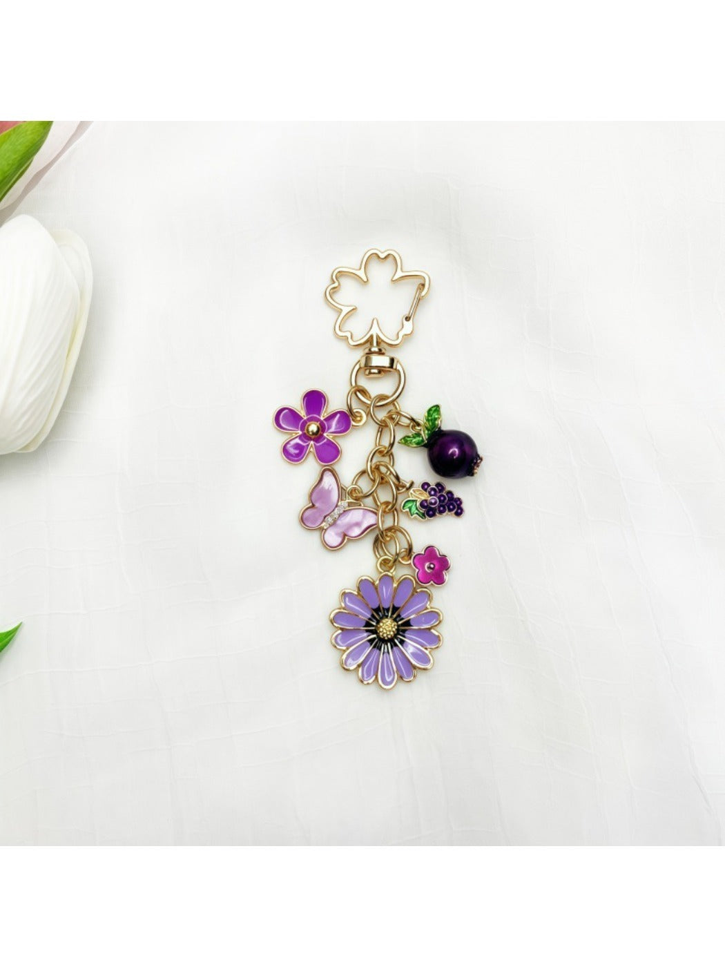 Hand holding the delicate daisy charm keychain with gold finish