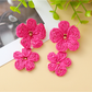 Model wearing Earedge floral pendant raffia drop earrings with a white top