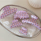 Close-up of Beau pink hair clip with white polka dots on a white background