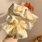 Yellow and white striped scrunchie displayed on a wooden surface