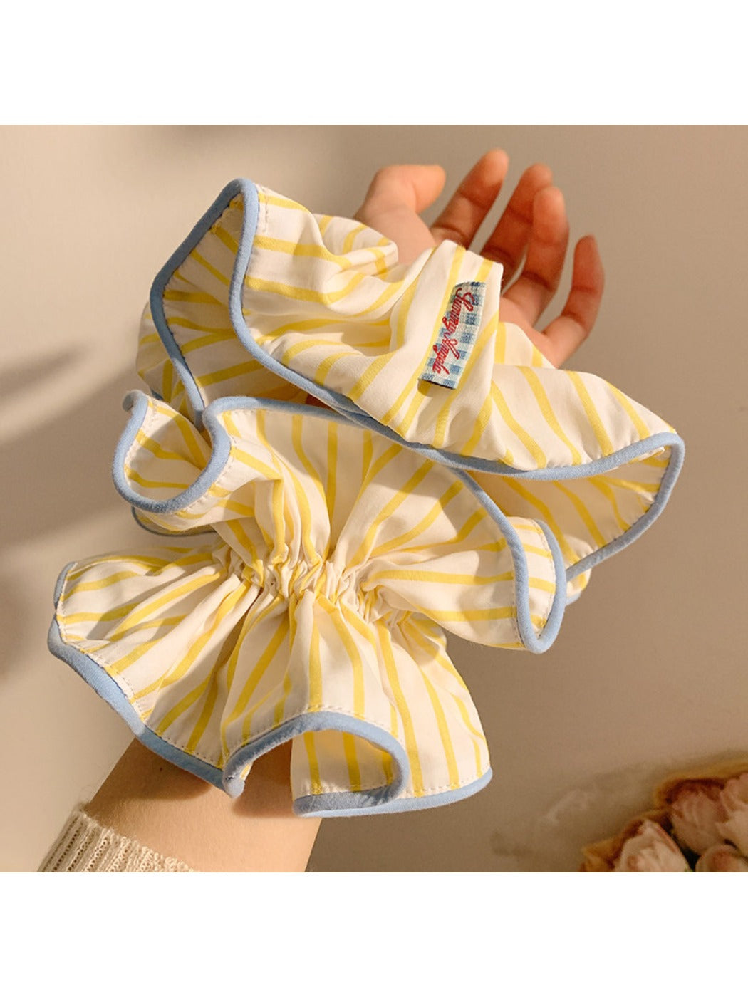 Yellow and white striped scrunchie displayed on a wooden surface