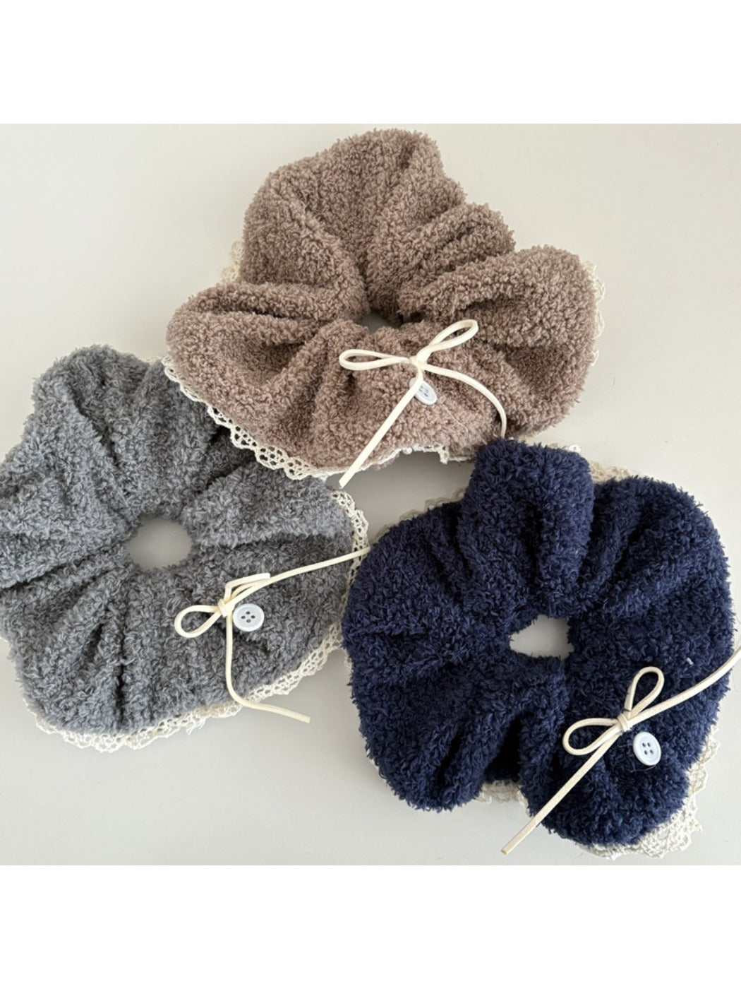 Close-up of a white lace scrunchie with a bow detail on a wooden surface