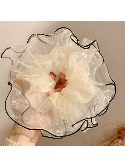 Beige tulle scrunchie arranged in a circular shape showing its volume and light fabric