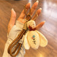 Bee charm keychain hanging from a backpack zipper pull