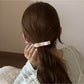 Hair tie featuring a soft fabric bow in pastel pink, styled on a wooden surface