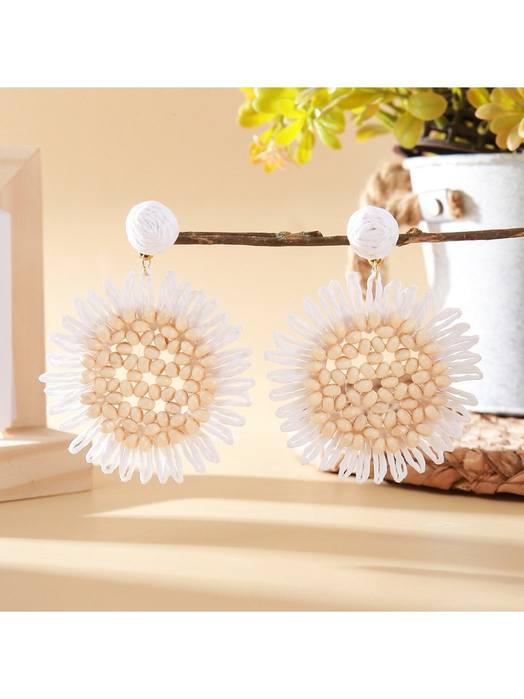 Sunflower drop earring hanging from a gold hook, showing detailed petal design