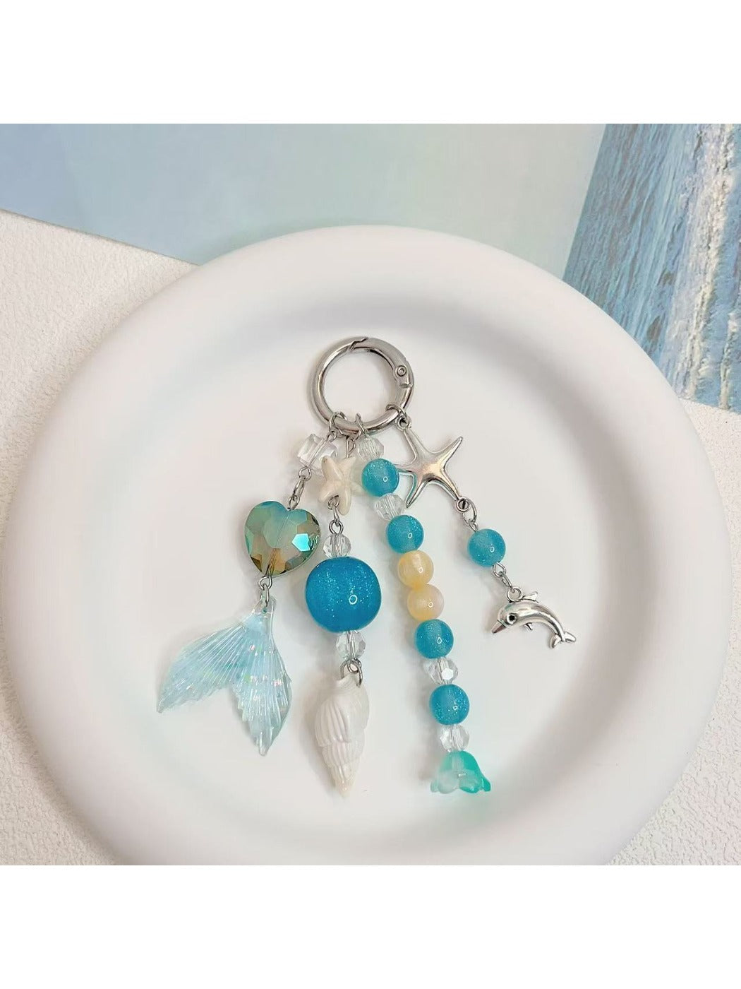 Ocean-inspired charm keychain held in hand showing size and detail