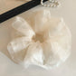 Beige tulle scrunchie styled on a wrist as a bracelet accessory