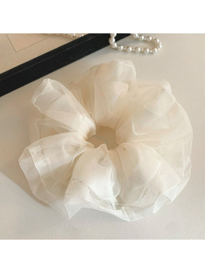 Beige tulle scrunchie styled on a wrist as a bracelet accessory