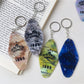 Diamond-shaped pendant keychain displayed hanging from a hook with bright colors
