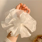 White scrunchie with layered ruffles displayed on a plain background