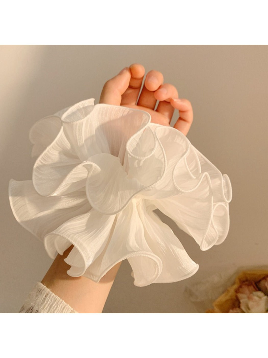 White scrunchie with layered ruffles displayed on a plain background