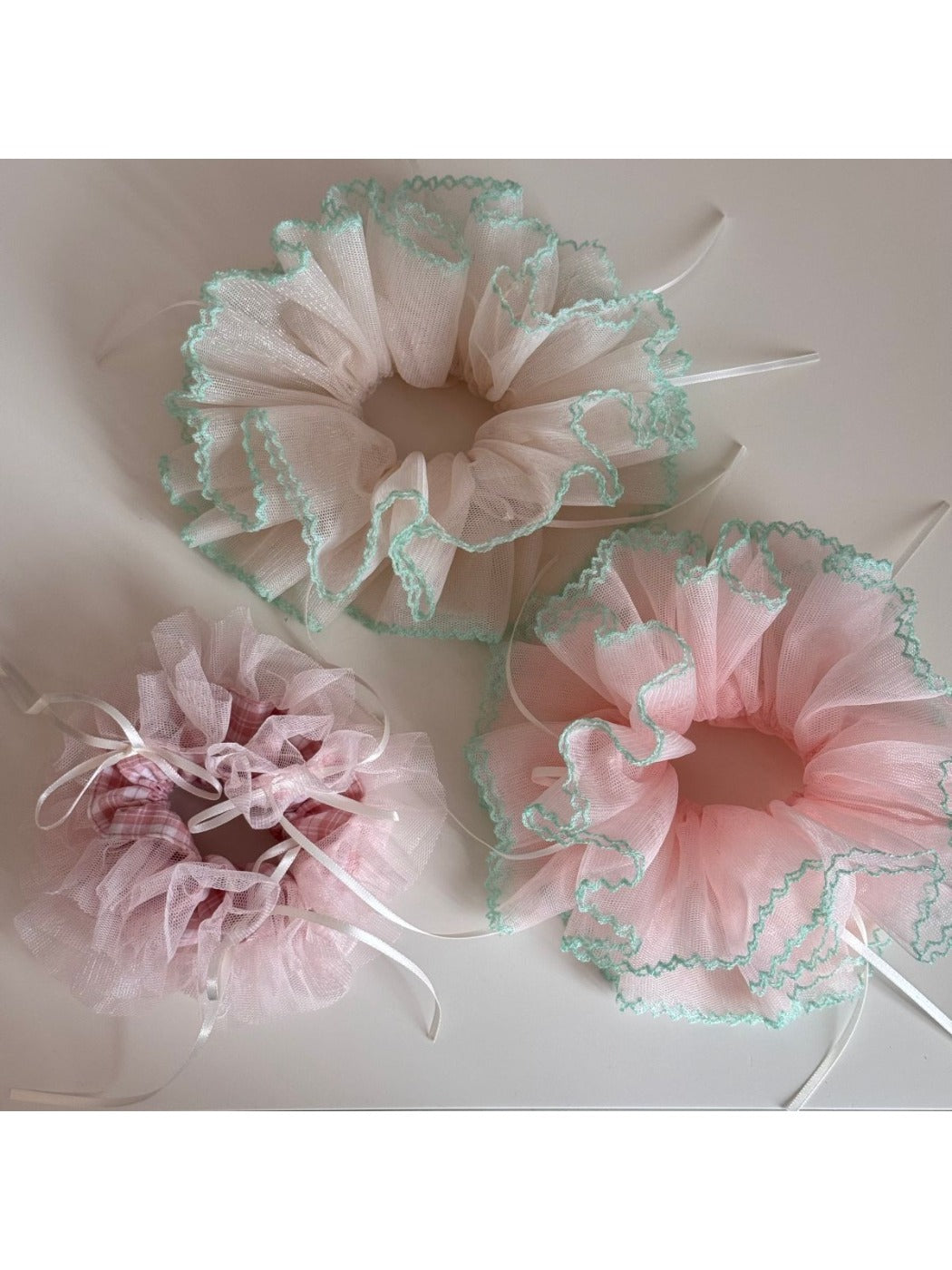 Close-up of Gifty Ribbon Knot Tulle Scrunchie in soft pink on white background