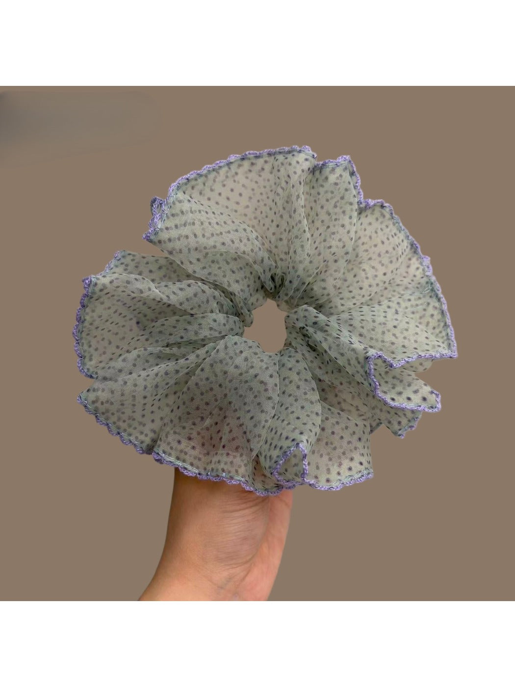 Purple scrunchie with white polka dots and purple trim on a white background