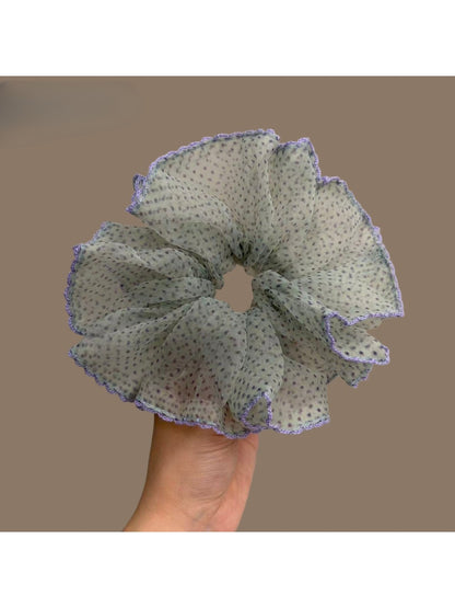 Purple scrunchie with white polka dots and purple trim on a white background