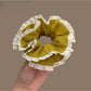 Close-up of green plaid fabric and white trim on scrunchie