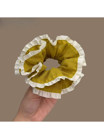 Close-up of green plaid fabric and white trim on scrunchie