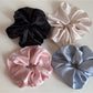 Side view of pink satin scrunchie adorned with clear rhinestones