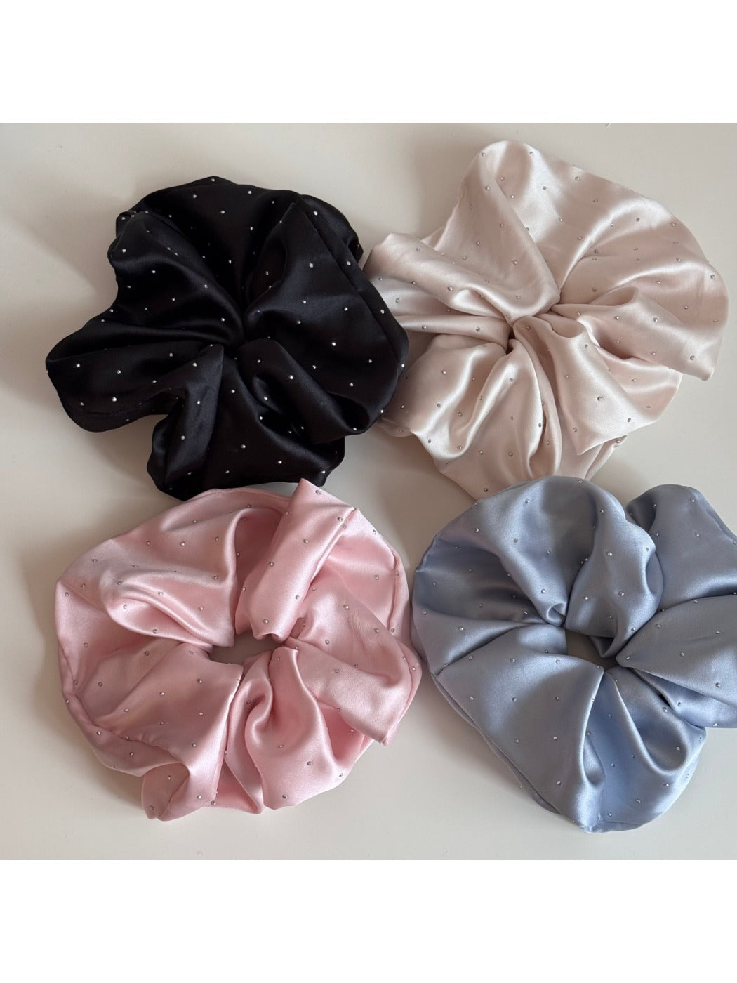 Side view of pink satin scrunchie adorned with clear rhinestones