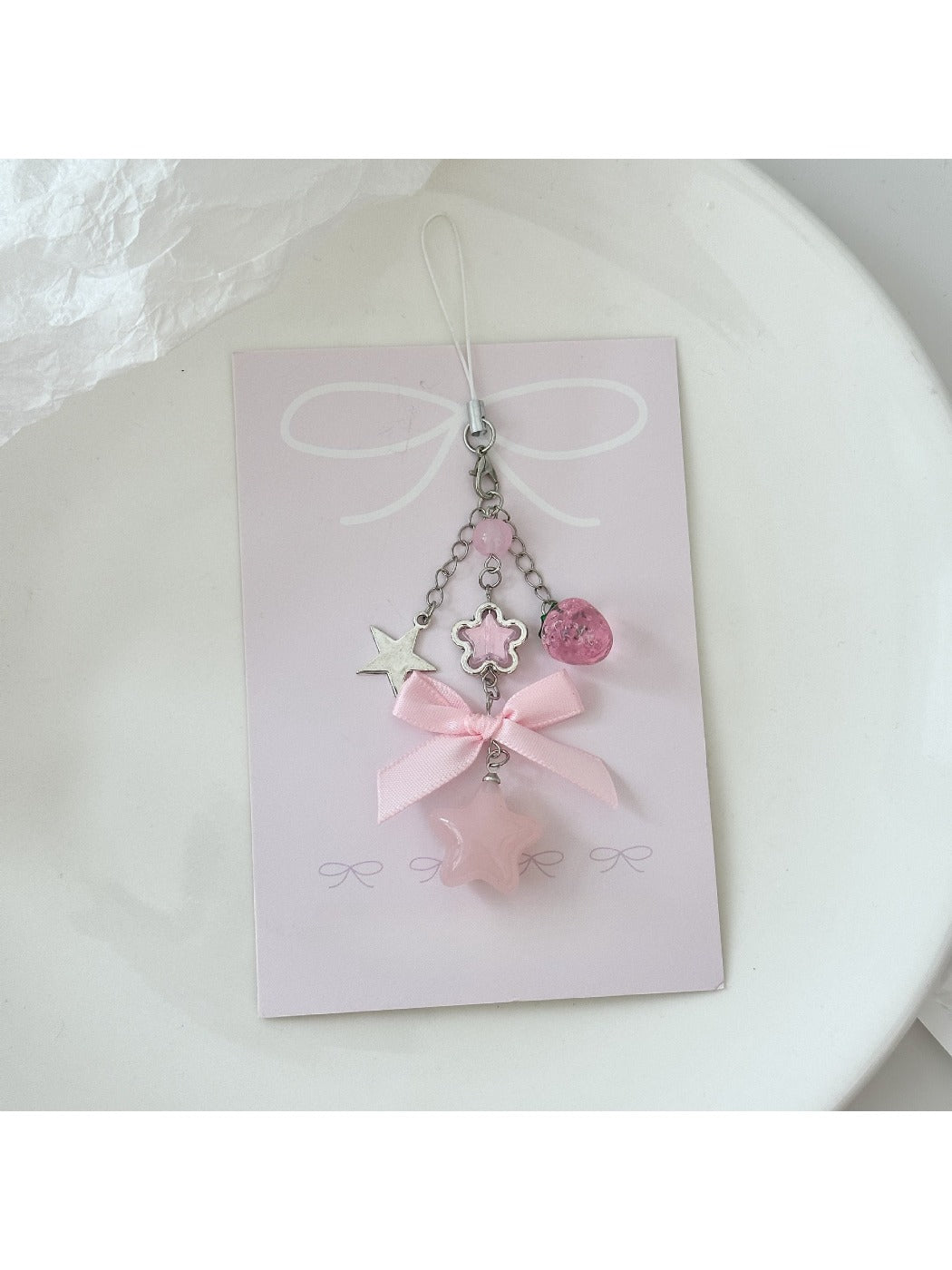Pink star keychain displayed on a wooden surface with soft lighting