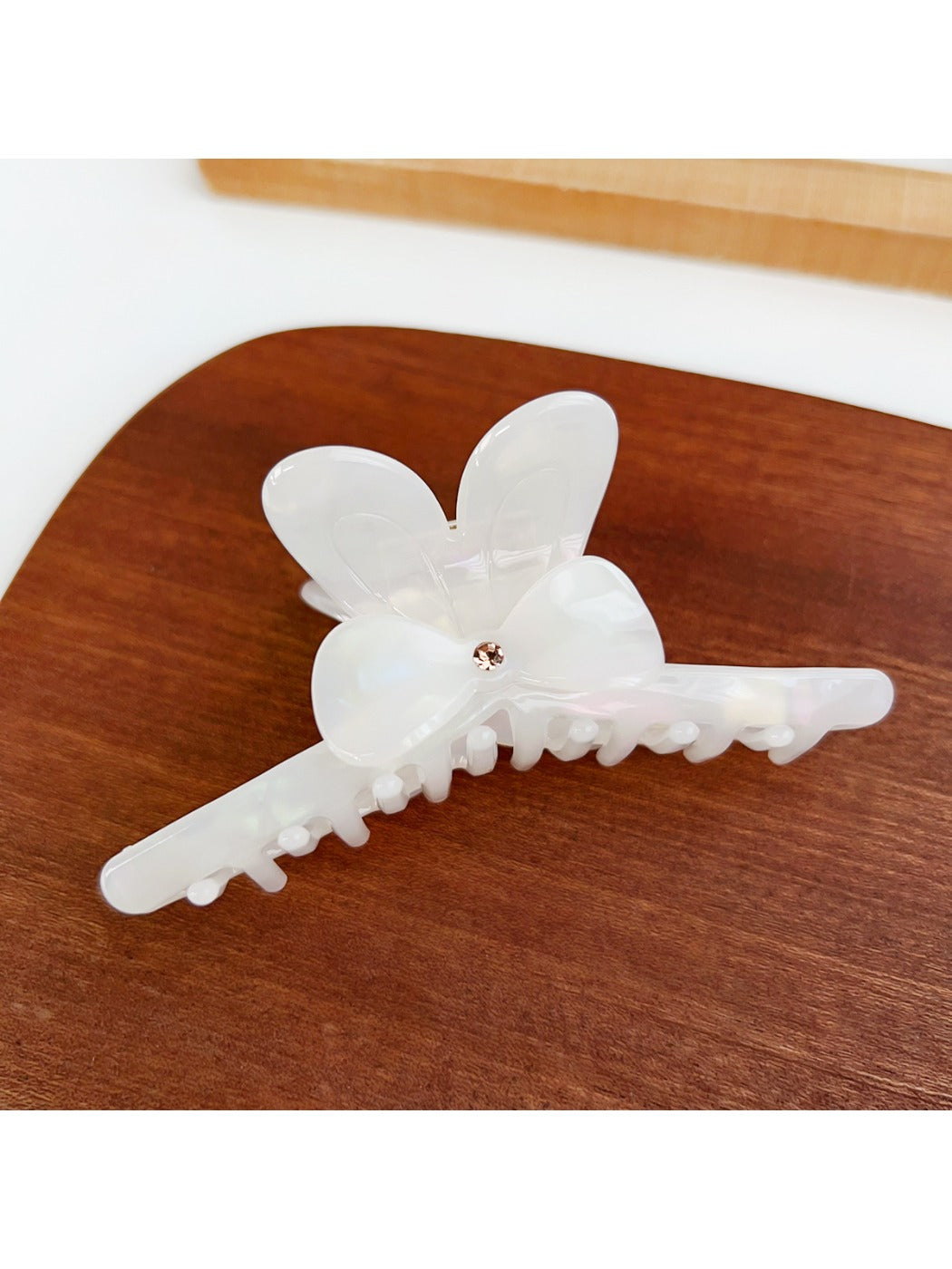 Beau minimalist bow hair claw clip held in hand against white background