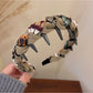 Gifty knitted fabric wrapped headband in light brown color on wooden surface