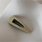 Beau pink hair clip with white polka dots resting on a fabric surface