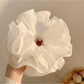 Side view of white ruffled scrunchie showing fabric texture and folds