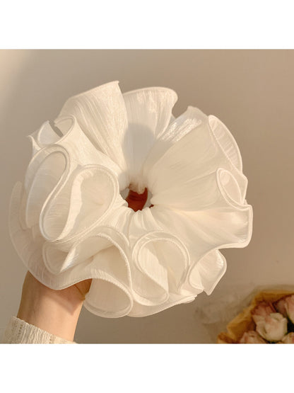 Side view of white ruffled scrunchie showing fabric texture and folds