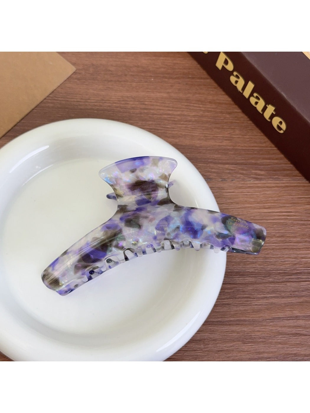 Beau acetate curved claw clip resting on white surface, angled view