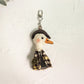 Person holding the duck charm keychain between fingers showing scale and detail