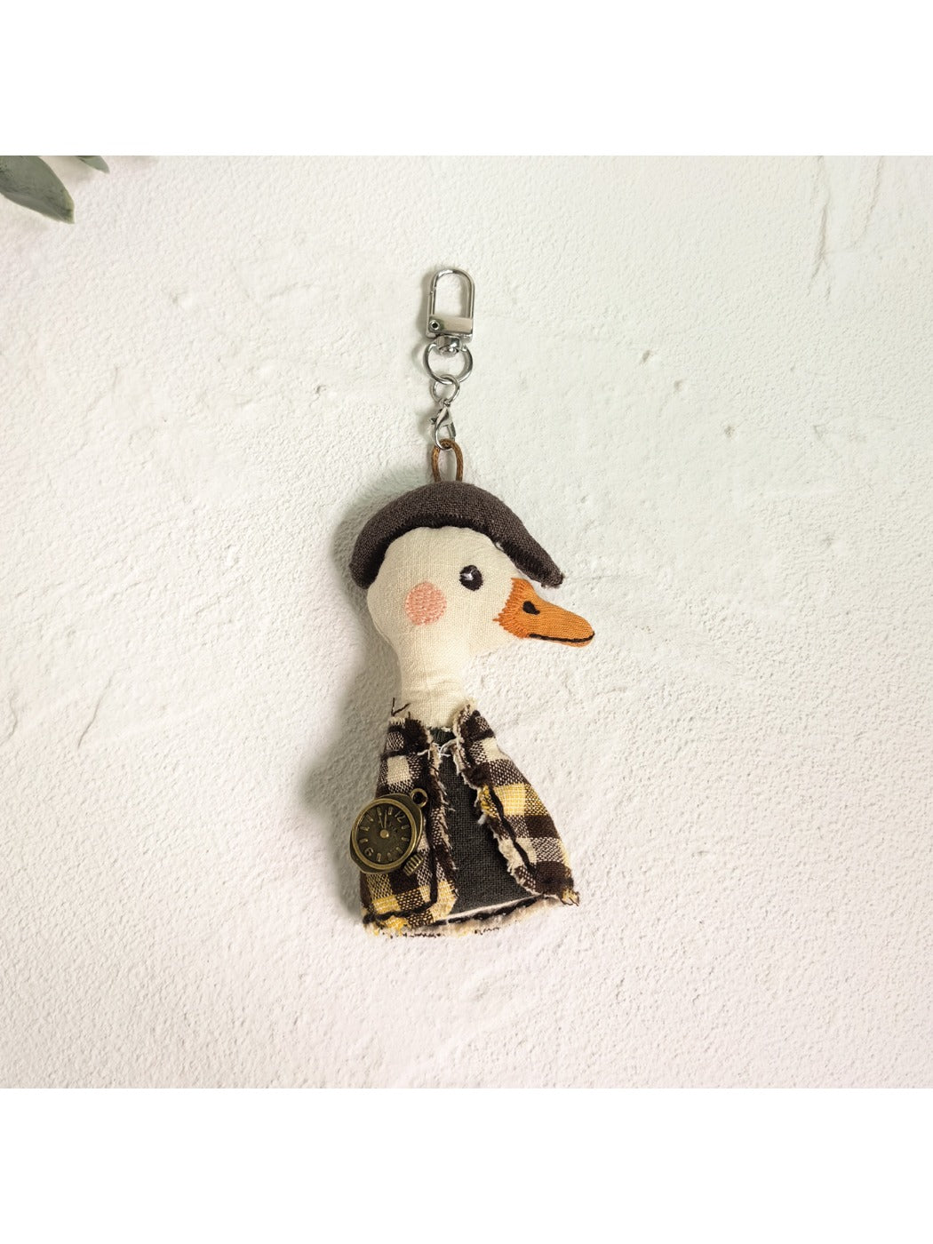 Person holding the duck charm keychain between fingers showing scale and detail