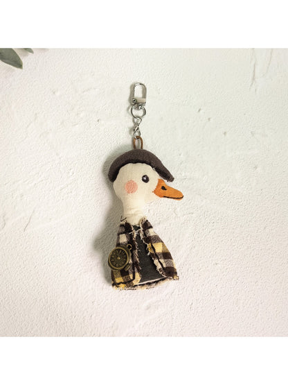 Person holding the duck charm keychain between fingers showing scale and detail