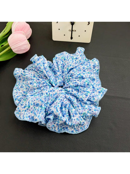 Scrunchie stretched to show elastic band inside black polka dot fabric