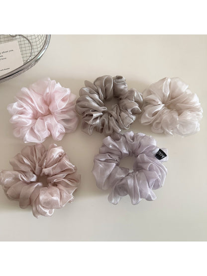 Flat lay of multiple solid color scrunchies arranged on a white background