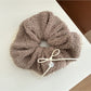 White lace scrunchie with bow detail held in hand showing texture