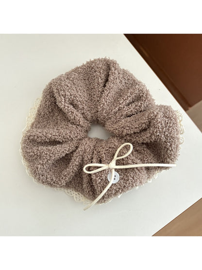 White lace scrunchie with bow detail held in hand showing texture