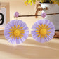 Sunflower shaped earrings hanging from a jewelry stand with soft shadows