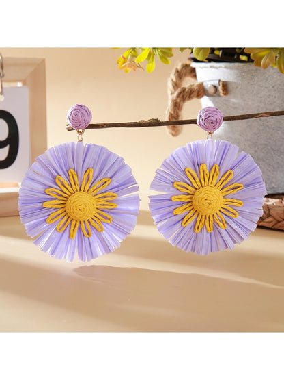 Sunflower shaped earrings hanging from a jewelry stand with soft shadows
