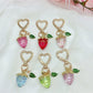 Hand holding Keypus strawberry charm keychain showing detailed texture